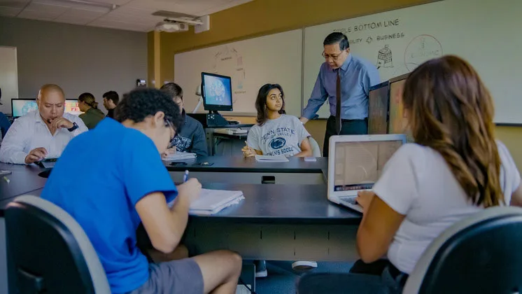 Photo of students in a classroom interacting with their instructor