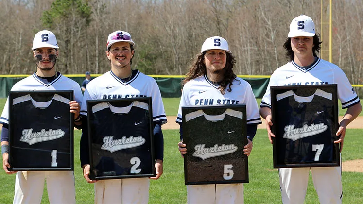 Photo of four members of the Hazleton baseball team holding up framed jerseys