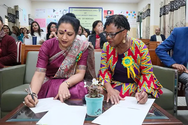 Two faculty members signing papers in India