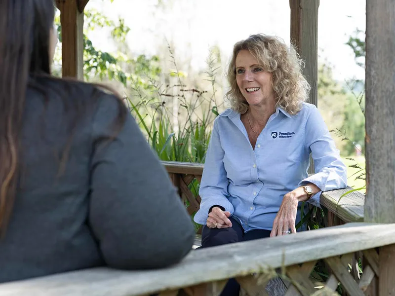 A student and a staff member talking outside on a bench