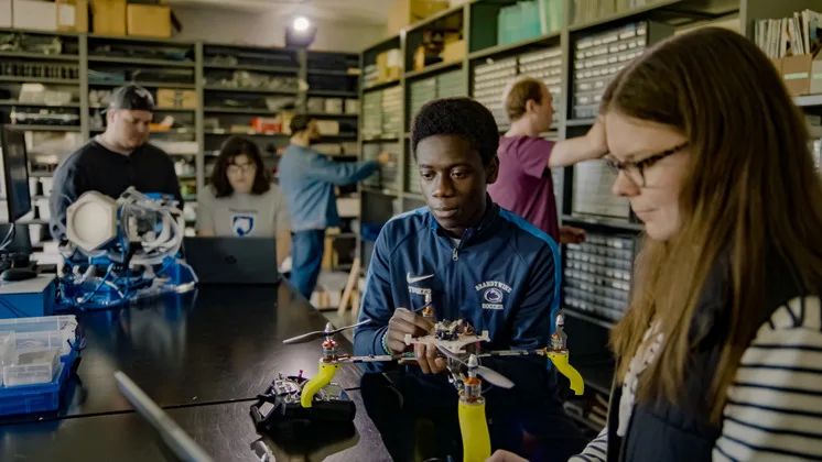 Photo of students working together with machines in a lab