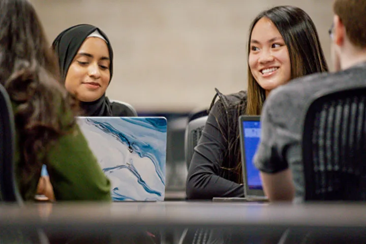 Photo of students with laptops sitting at a table