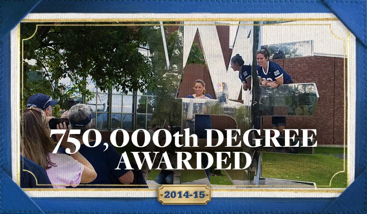 Students posting for a photo on the We Are statue on campus with overlayed text reading "750,000th degree awarded 2014-2015."