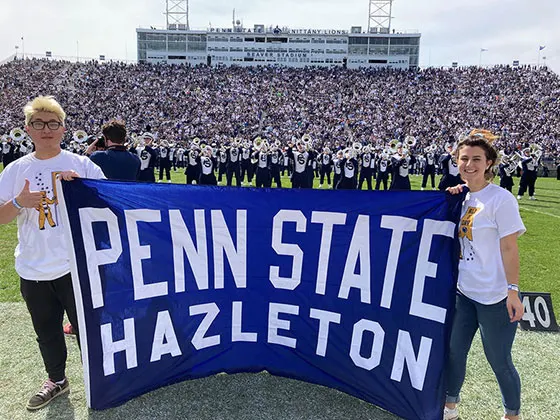 Photo of Hazleton students holding a banner representing their campus at a Penn State football game
