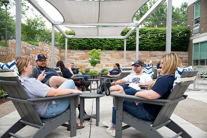 Photo of students sitting and talking in Adirondack chairs