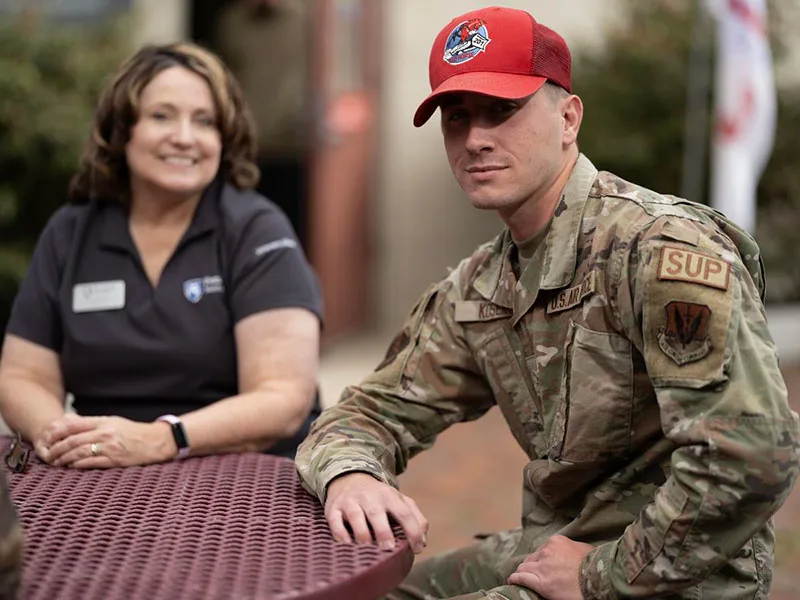 Photo of an adult learner in their Air Force uniform sitting a table with a Penn State staff member