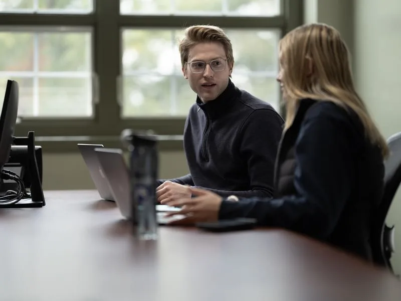 Staff consulting student in an office with computers on desk