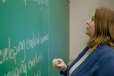 Photo of professor writing on a chalk board