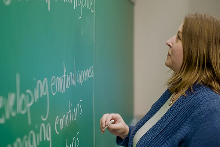 Photo of professor writing on a chalk board