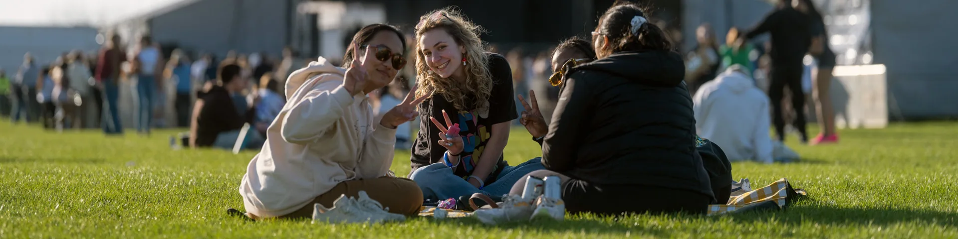 photo of students sitting in the grass using their fingers to give a "peace sign"