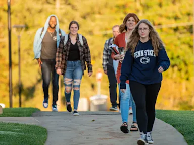 Students walking outside with yellow leaves in background