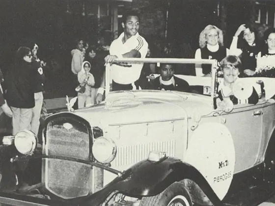 A group of cheerleaders ride in a convertible car in the 1979 Homecoming parade.