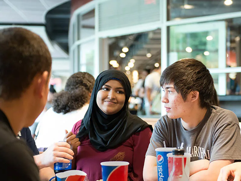 Students siting at a table in a dining hall together