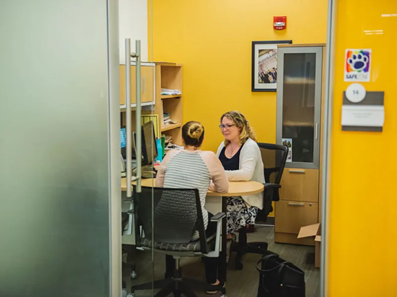 A student is counseled in a yellow room by a Penn State staff member