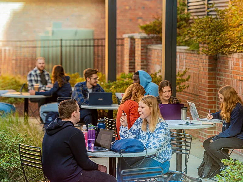 Students sitting at tables in an outdoor courtyard at Penn State New Kensington.