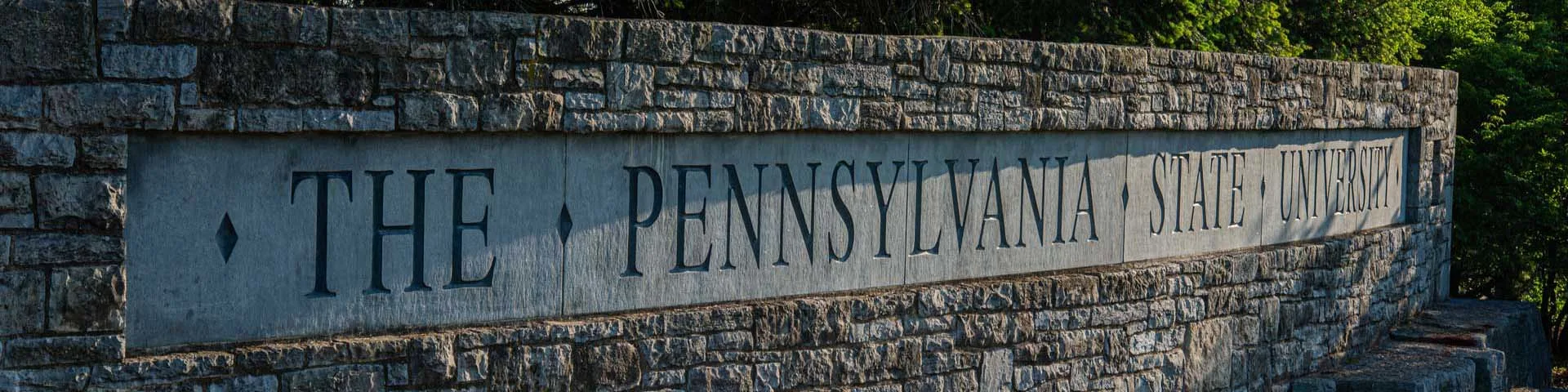 Photo of a bronzed University seal hanging on a stone wall