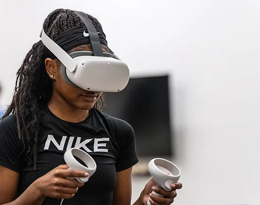 Student using virtual reality goggles and hand controls.