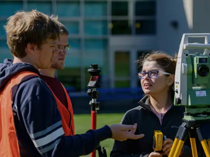 Three people using surveying equipment at Penn State Wilkes Barre.