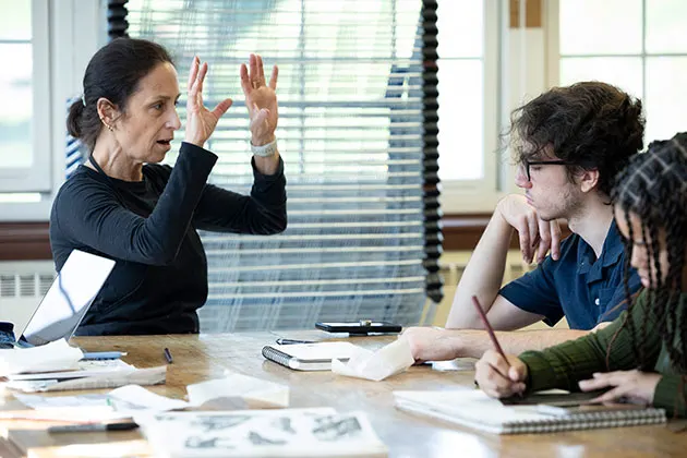 Instructor sitting at table with two students in classroom