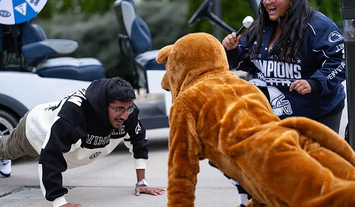 A student and the Nittany Lion mascot doing push-ups. 