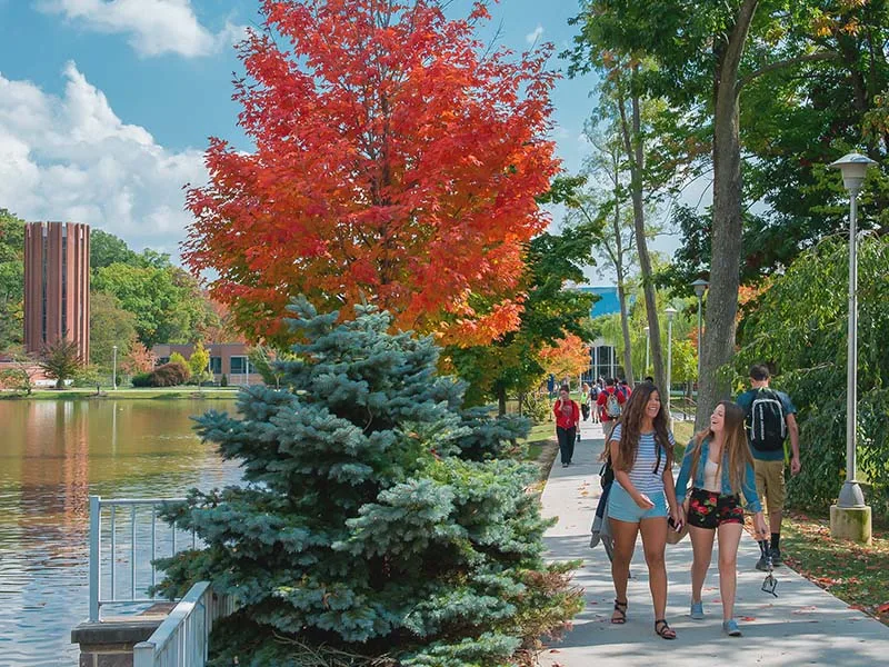 People walking on a sidewalk next to a pond at Penn State Altoona.