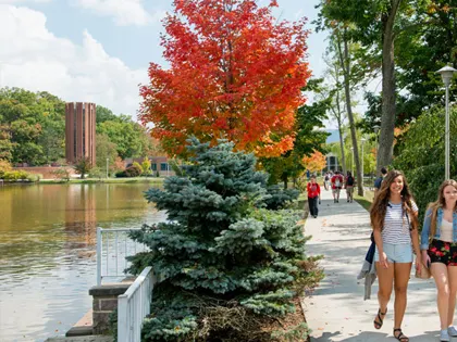 People walking on a sidewalk next to a pond at Penn State Altoona.