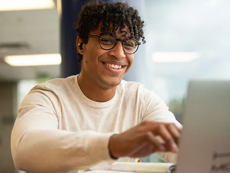 Smiling student working on laptop.