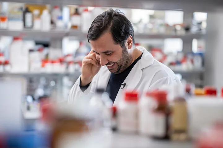 Researcher standing in their lab, looking down and smiling