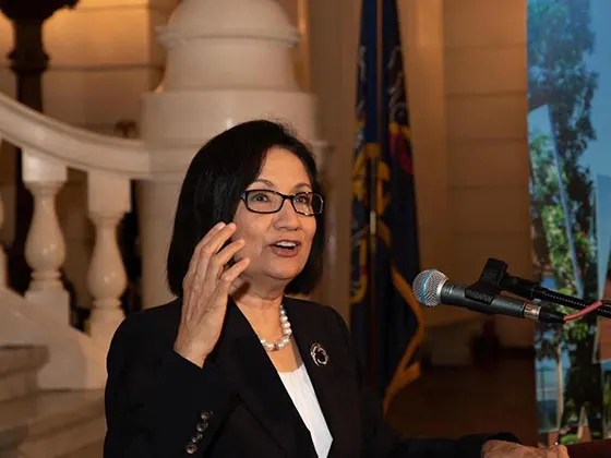 President Neeli Bendapudi stands at a podium speaks in the Pennsylvania Capitol rotunda.