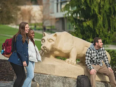Three students talking at the Nittany Lion Shrine at the Penn State Berks campus.