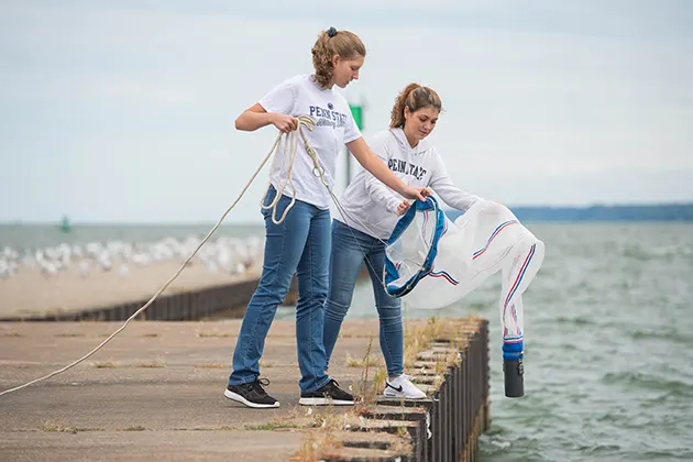 Two students conducting invasive species research on a Lake Erie dock.