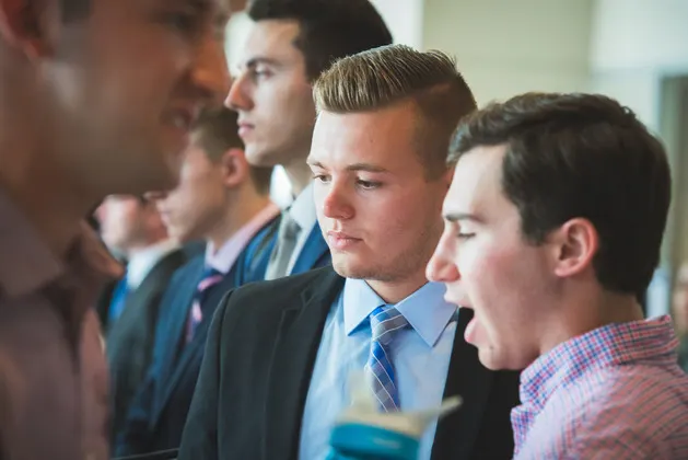 Photo of a group of students speaking to recruiters at a career fair