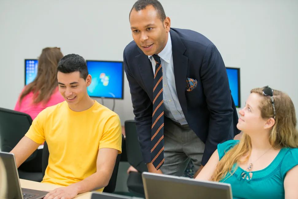 Teacher helping students in a lab.