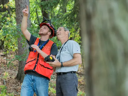 Two people in safety uniforms pointing to the sky at Penn State Mont Alto.