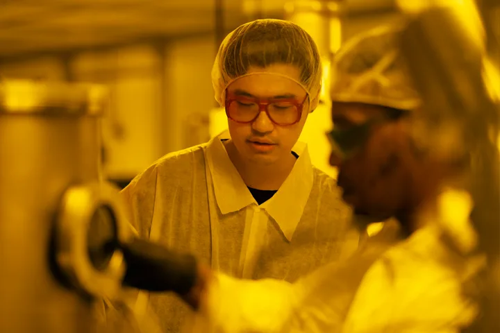 Two semiconductor students in protective clothing in a research clean room