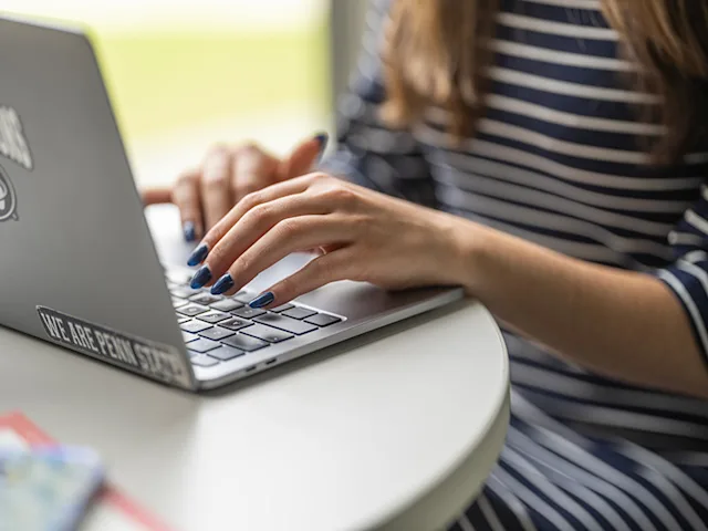 Penn State student typing on laptop.
