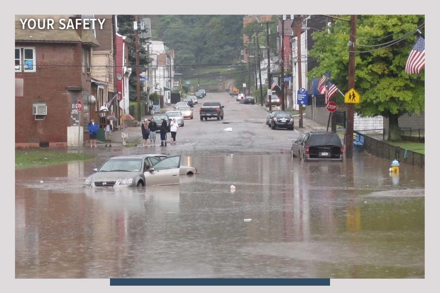 A flooded street with 3 cars in the water. People stand nearby observing. There is an overlay that says: Your Safety