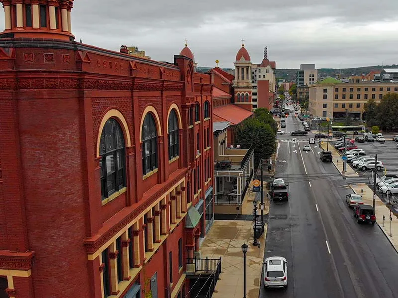 An image of buildings and streets framed by rolling hills in the background.