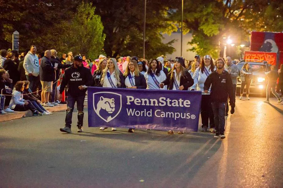 Students marching in Homecoming Parade holding a World Campus banner