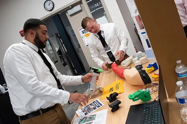 Two students working on an electronic model of an arm.