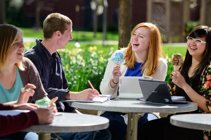 Students outside sitting at tables eating ice cream