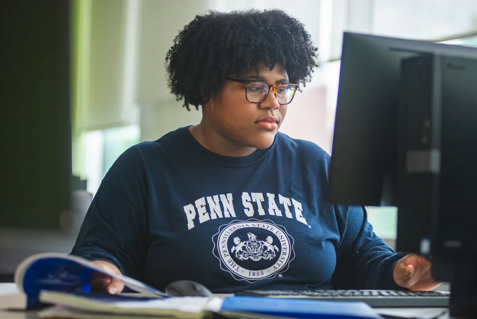 Student at desk working on computer.