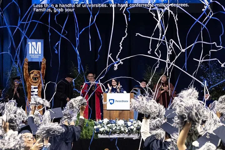 Blue and white streamers fall from the ceiling while a mascot holds a sign 