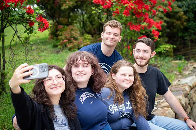 Photo of students sitting together outdoors and posing for a selfie