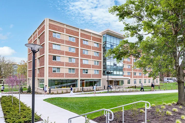 Photo of a residence hall exterior with students walking out front