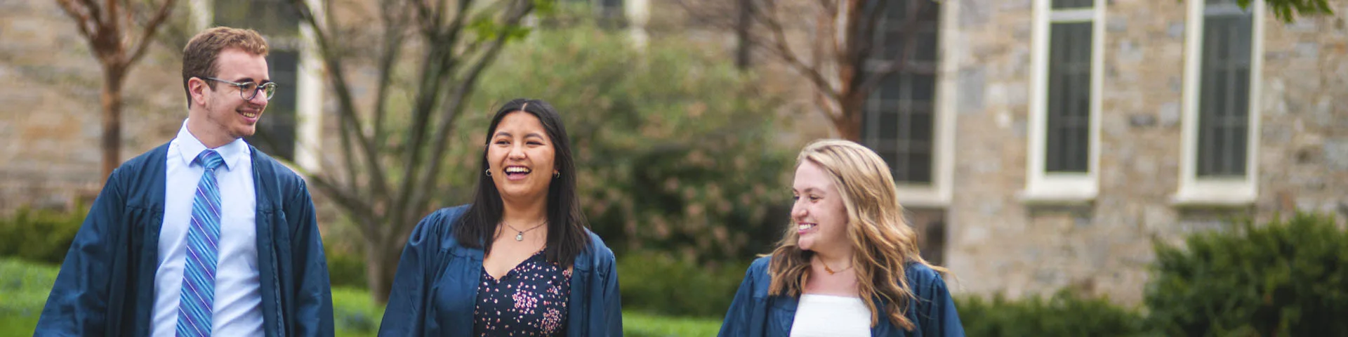 Three students in graduation robes. 