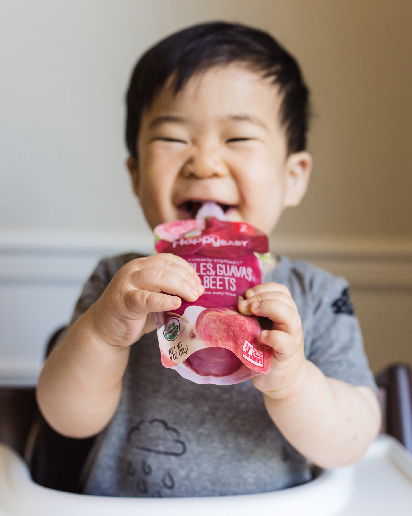 baby eating clearly crafted pouch in highchair.