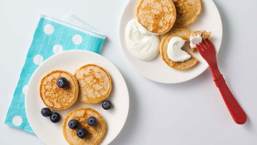 Yogurt on pancakes and blueberries on pancake above a white polkadot and blue napkin