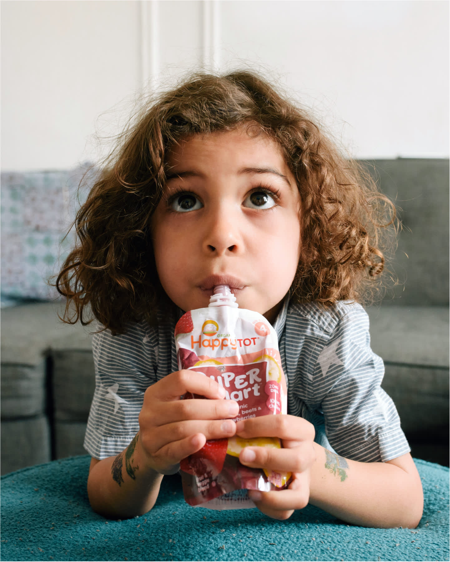Toddler watching eating pouch in living room.