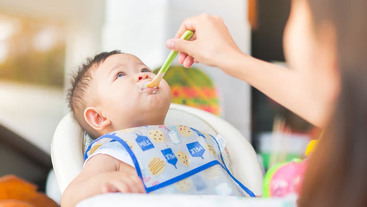 Baby in a high chair getting spoonfed